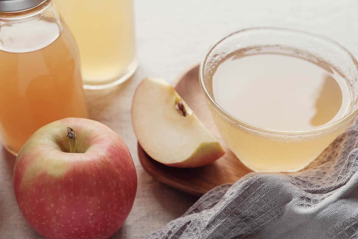 apple cider vinegar in small glass bowl with fresh apples.