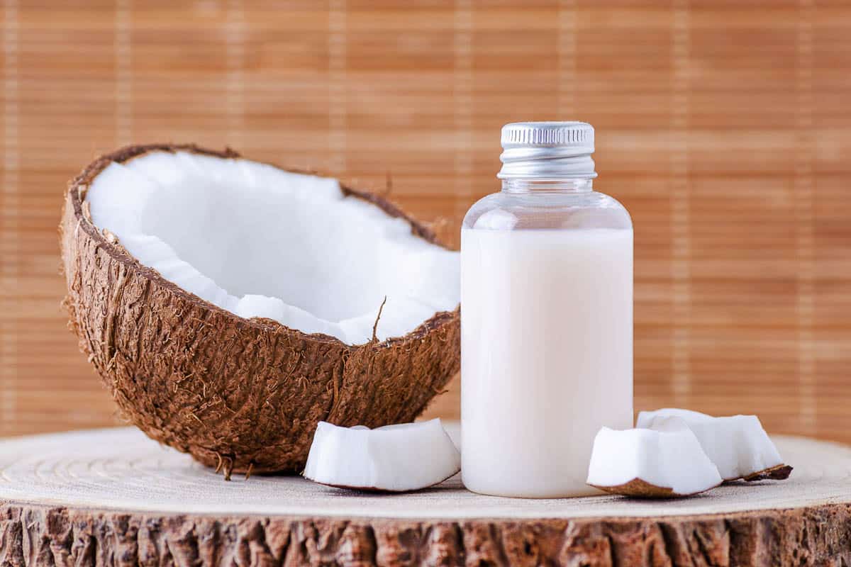 coconut milk in glass bottle next to coconut