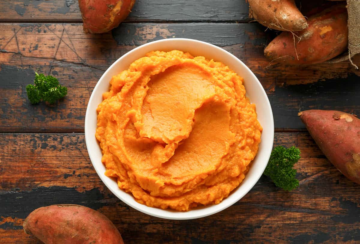 Mashed Sweet Potatoes in white bowl on wooden rustic table. Healthy food.