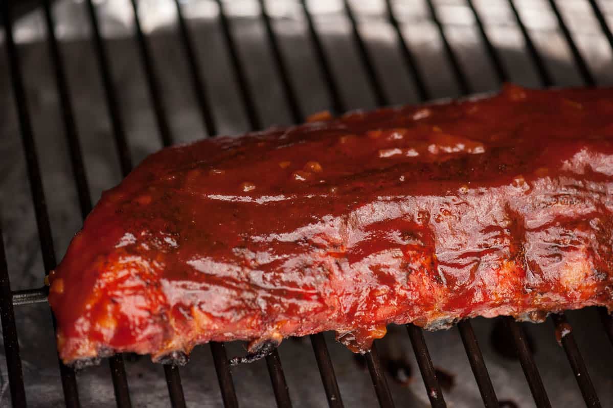 baby back ribs on grill covered in barbecue sauce