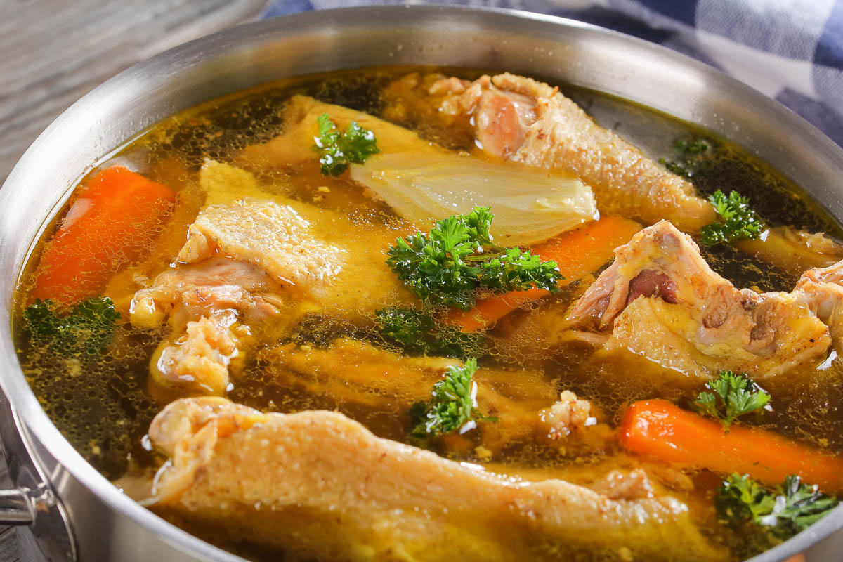 pot of chicken broth with pieces of chicken and vegetables.