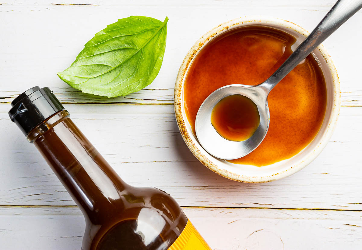 Worcestershire sauce in a bowl with spoon and bottle.