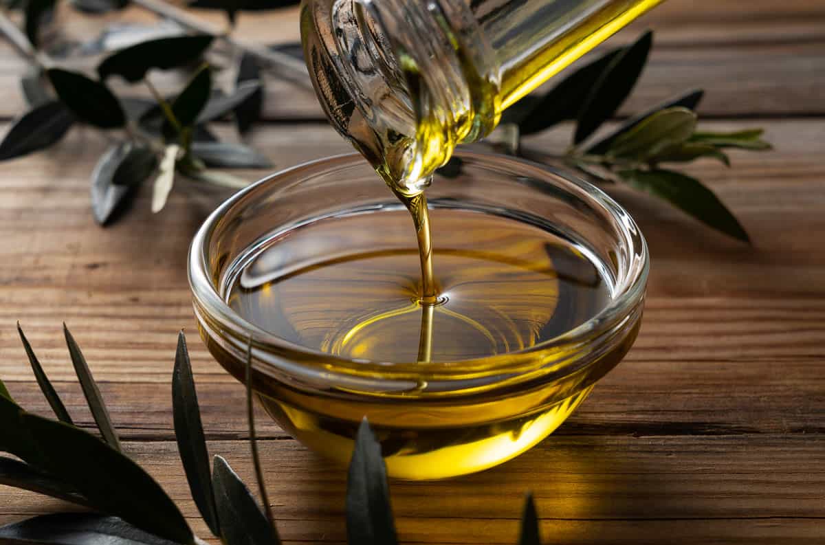 Pouring olive oil into a small glass bowl.