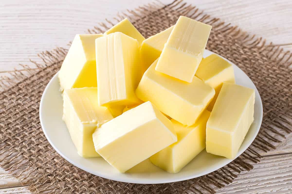 Rectangular pieces of fresh yellow butter on a white saucer.
