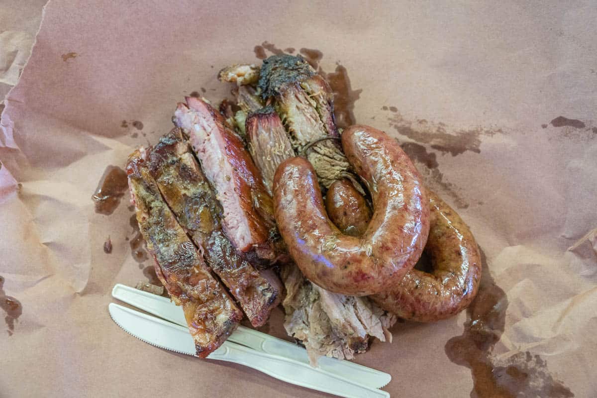 Fresh sausage and barbeque ribs served Texas-style on butcher paper with plastic utensils.
