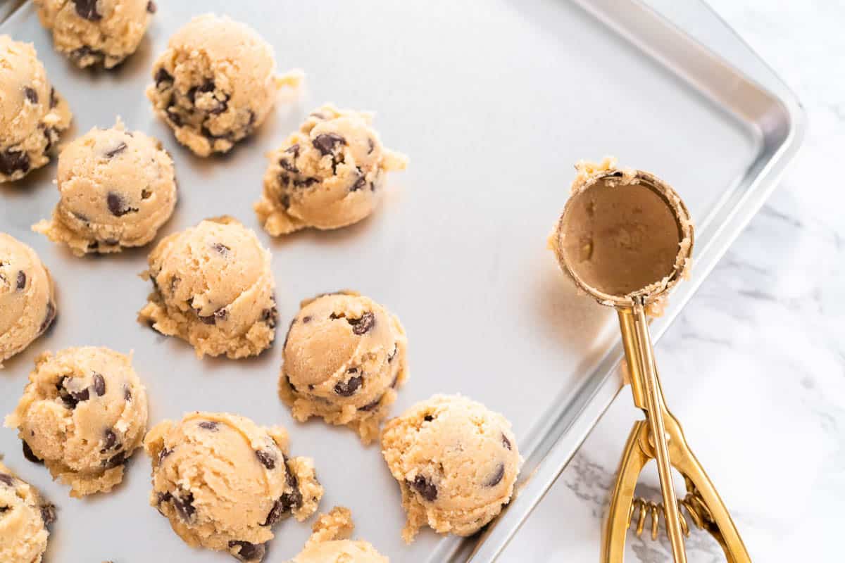 Homemade chocolate chip cookies dough scoops on a baking sheet.