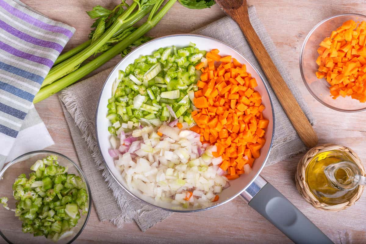 Cooking carrot and celery onion vegetable dressing, chopped ingredients for Mirepoix or Soffritto in a skillet.