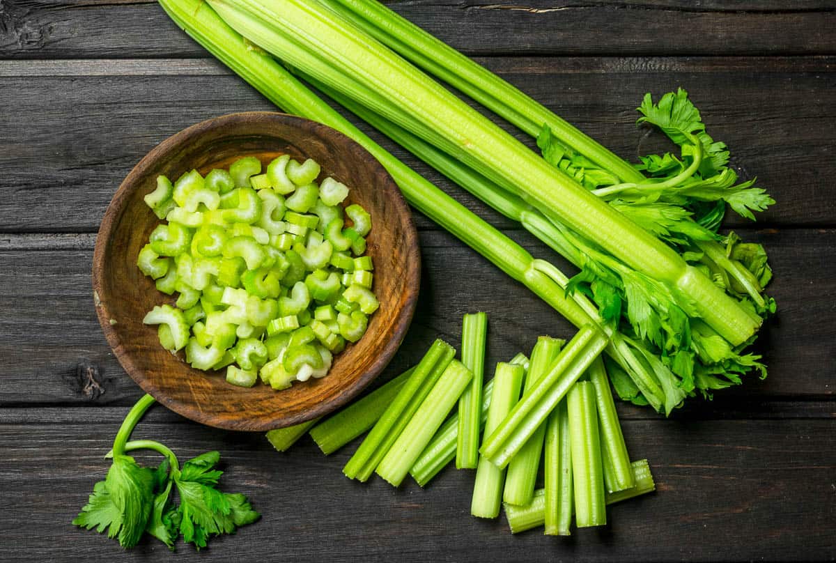 Pieces of celery in a wooden bowl. On black wooden background.