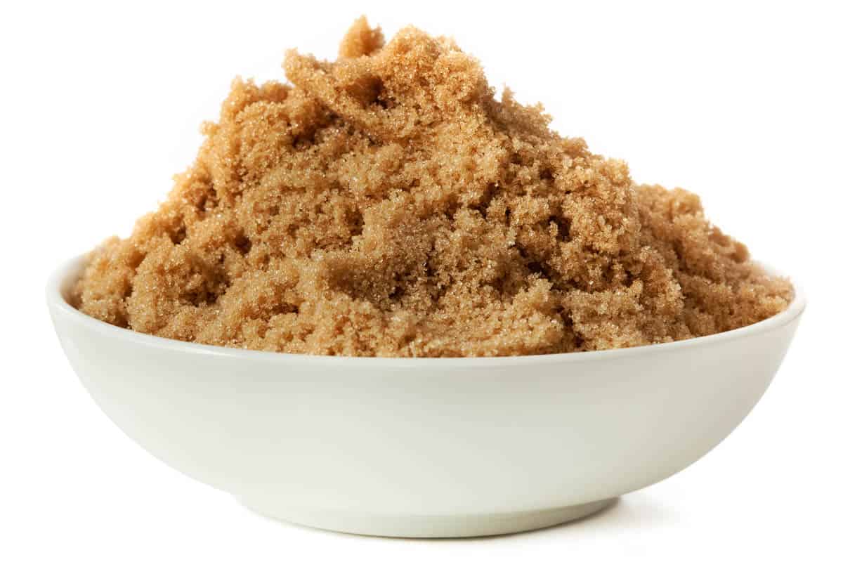 Small bowl of brown sugar, isolated on white.
