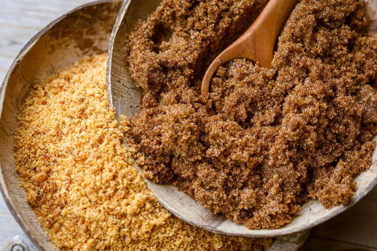 Soft brown dark sugar and unrefined sugar cane in bowls.