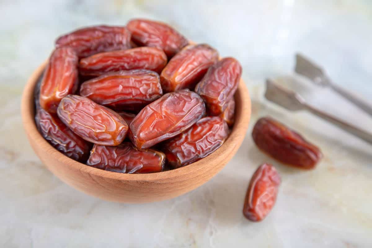 Bowl of dates fruit on colorful marble background.