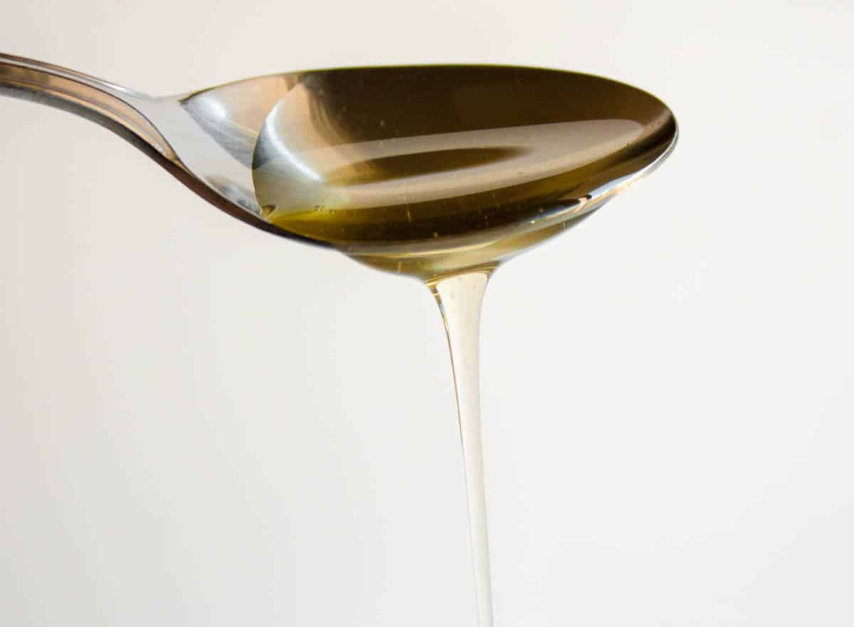 Agave nectar running off a metal spoon.