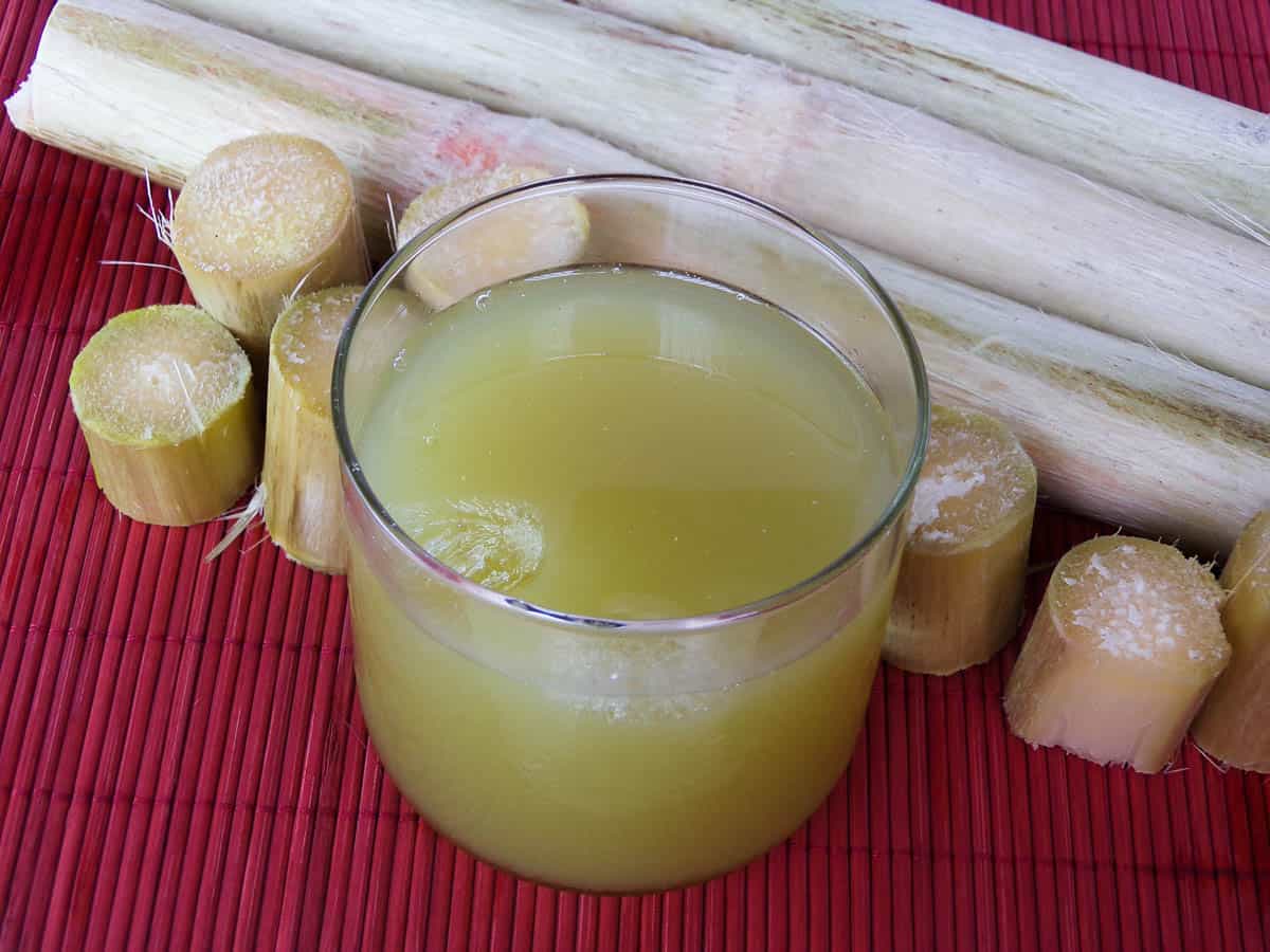 Sugar Cane Juice next to fresh sugar cane.