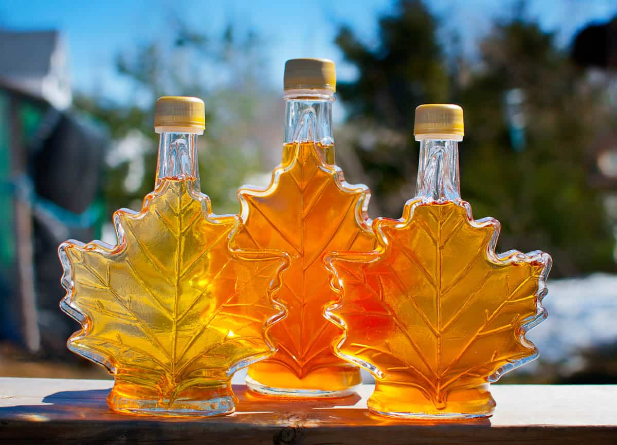 Three bottles of maple syrup shaped like maple leaves.