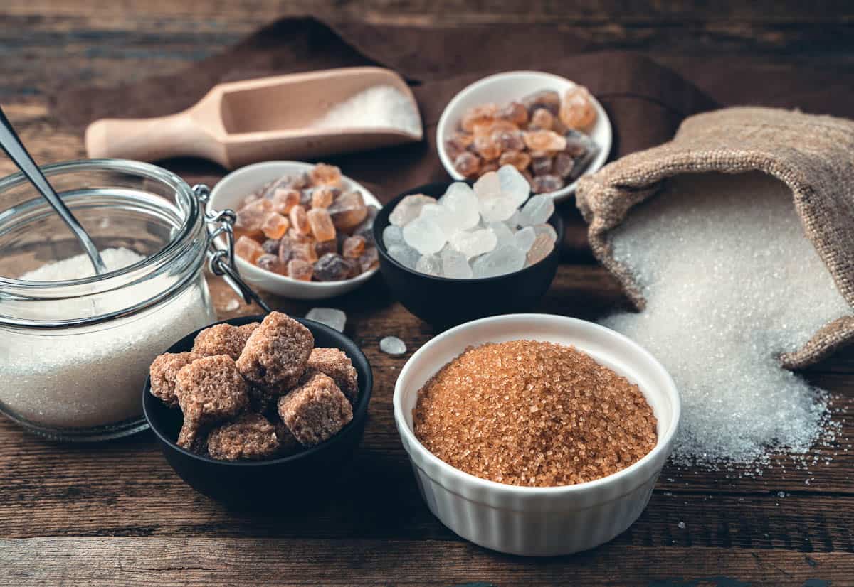 Many different types of sugar on a wooden background.