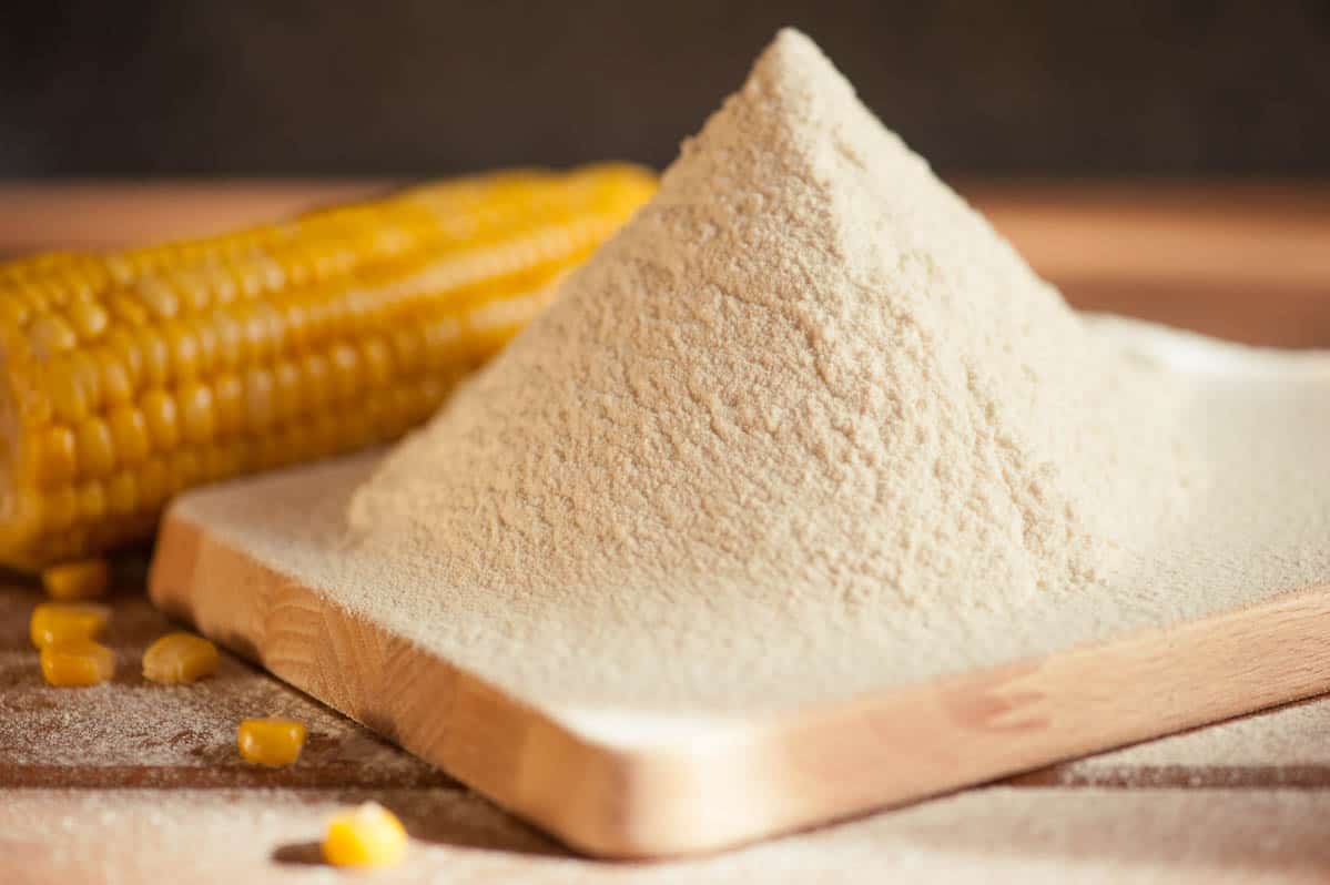 corn flour and corn on the cob on a wooden table.