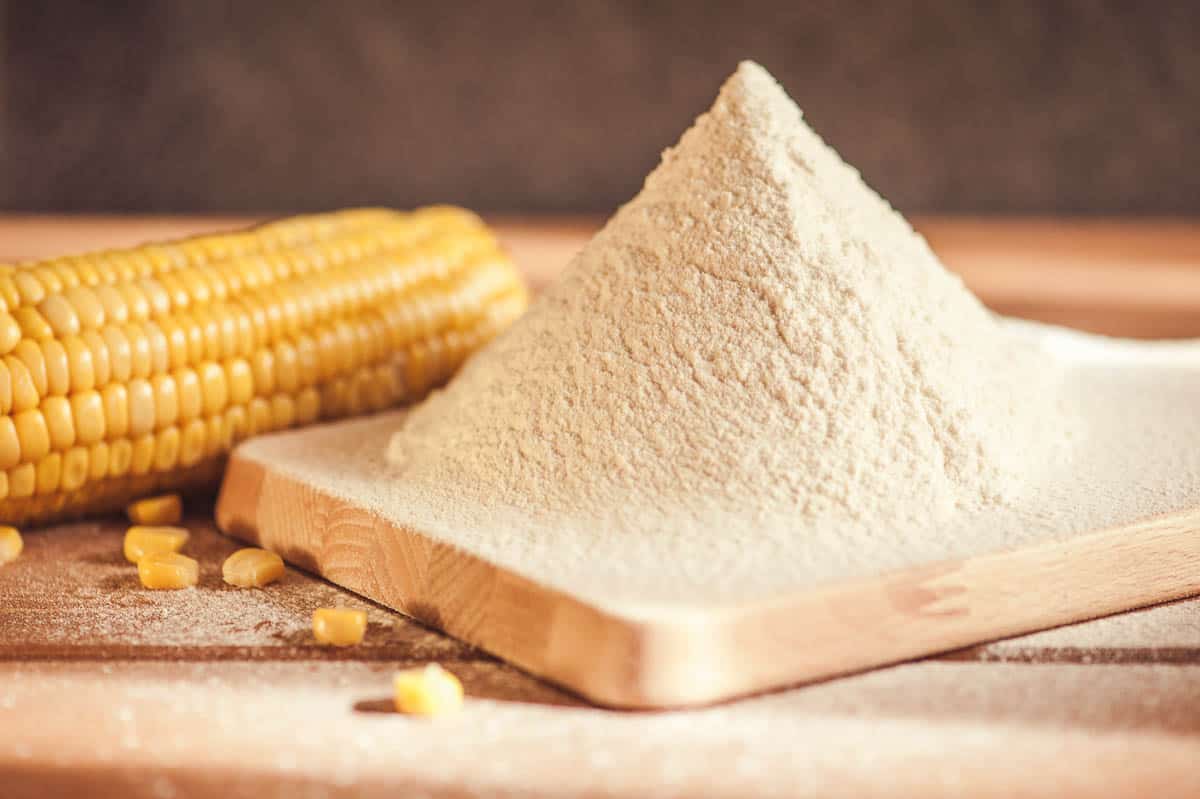 corn flour and corn on the cob on a wooden table.