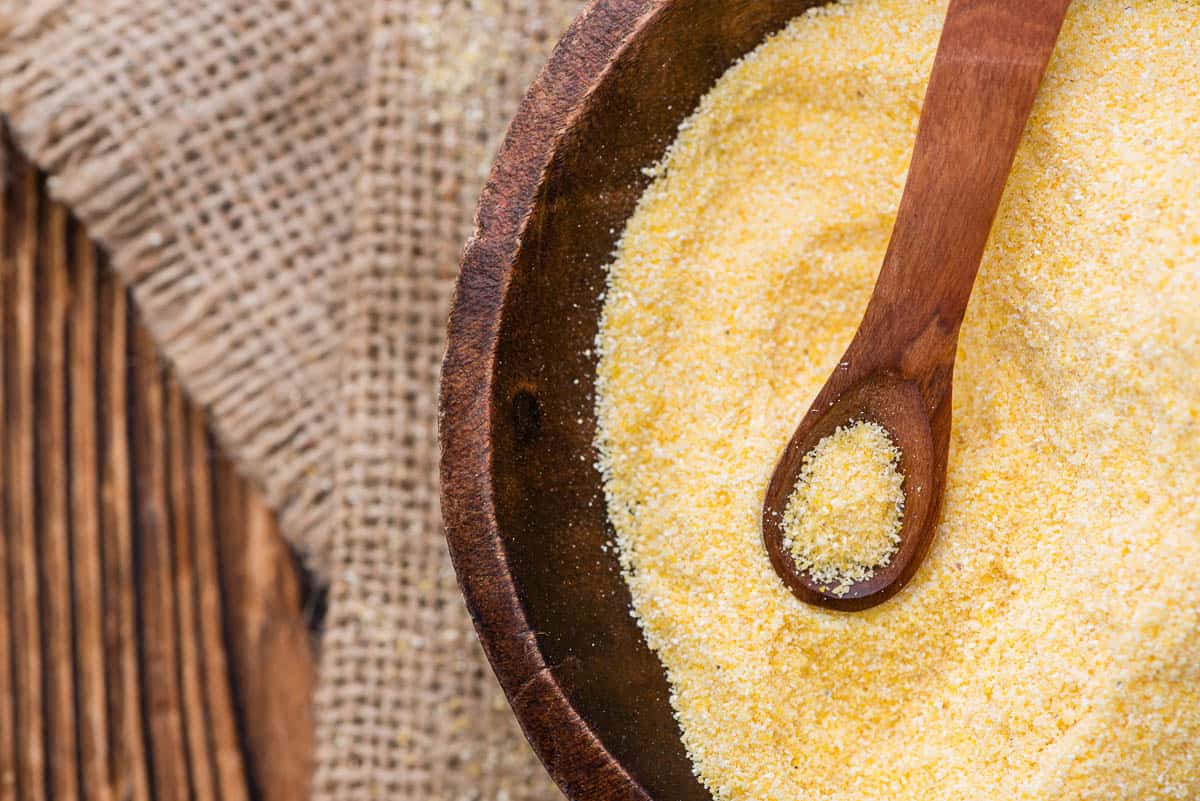 Portion of fresh Cornmeal (close-up shot) on rustic wooden background.