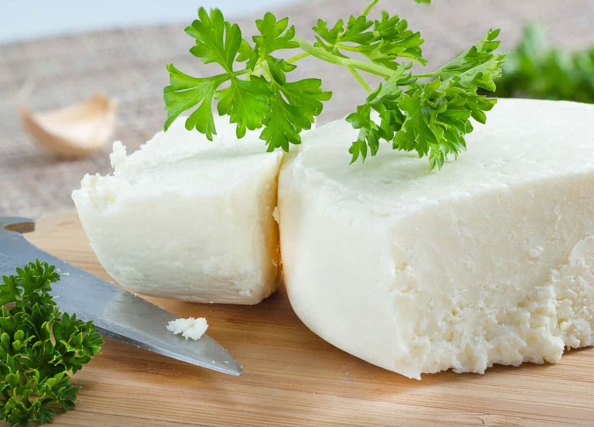 Cotija cheese with cilantro on cutting board.