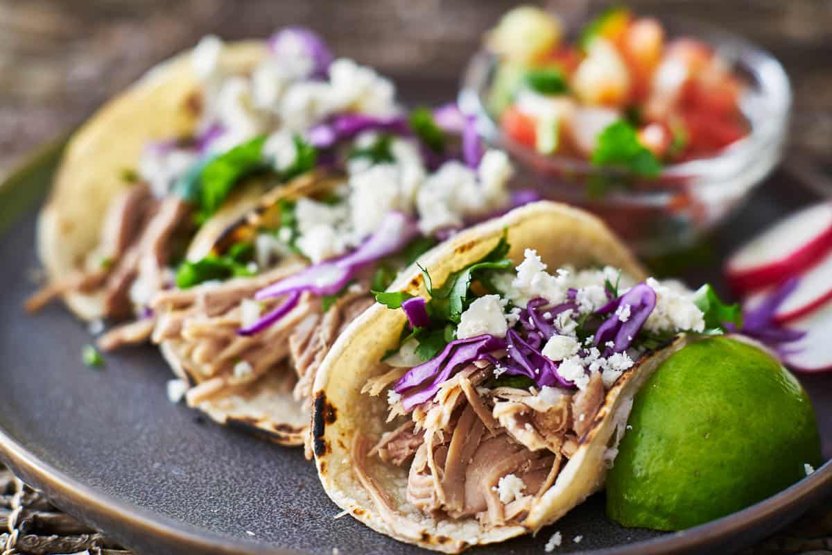 mexican street tacos with seasoned pork carnitas, red cabbage and queso fresco cheese.
