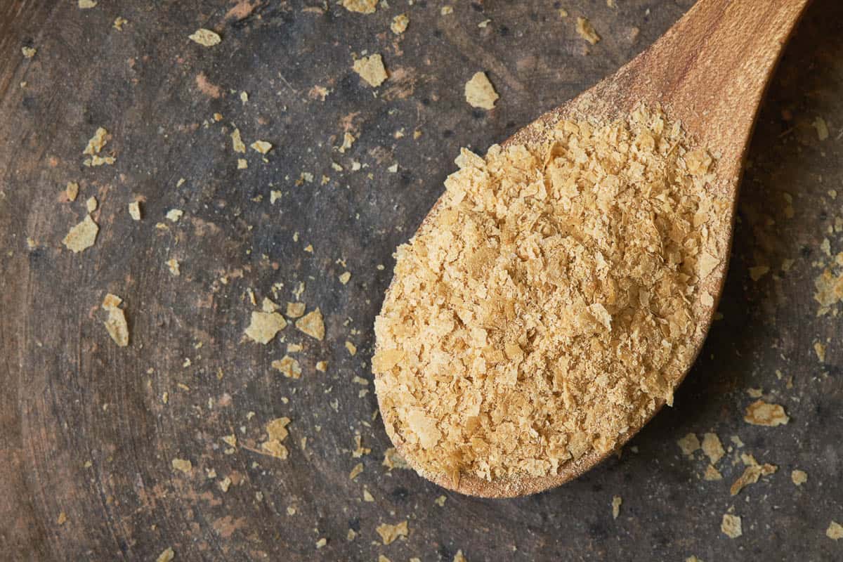 Nutritional brewers yeast flakes in wooden spoon.