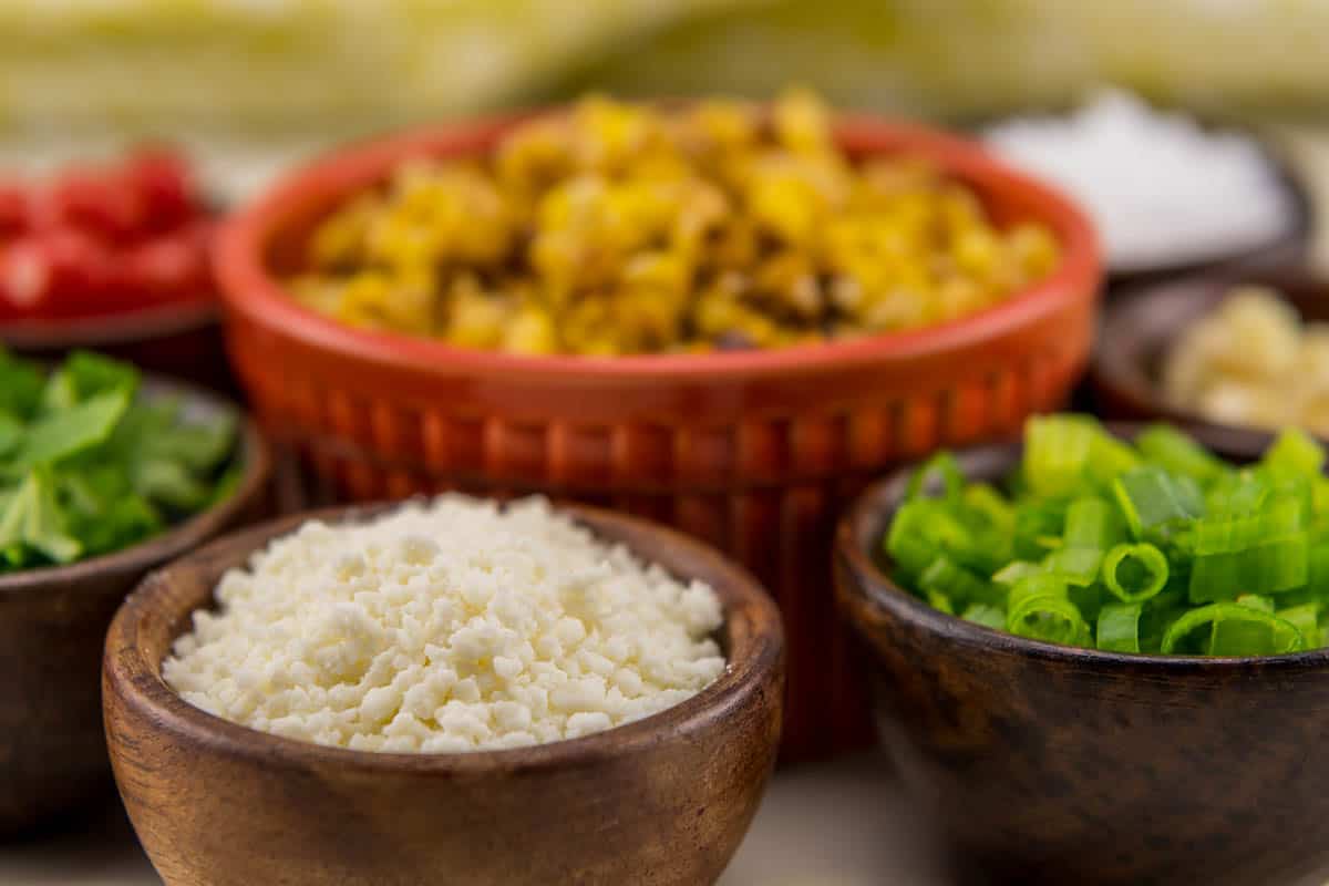 Crumbled Cotija Cheese in Wooden Bowl with other Mexican food ingredients.