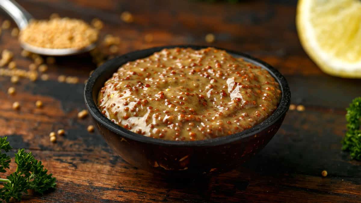 whole grain mustard in bowl on wooden table.