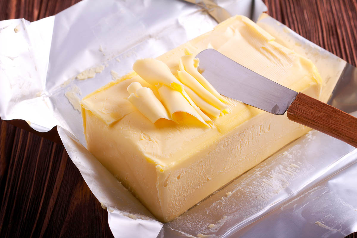 Butter over paper package on wooden table.