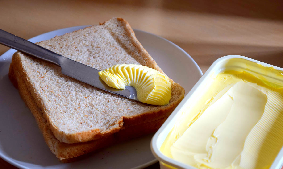 spreading margarine butter onto bread.