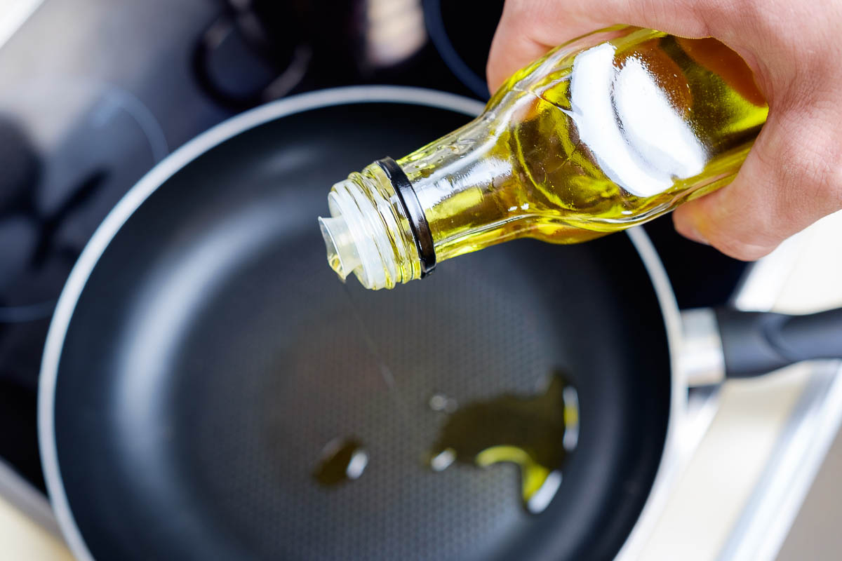 overhead shot of pouring oil into black pan.