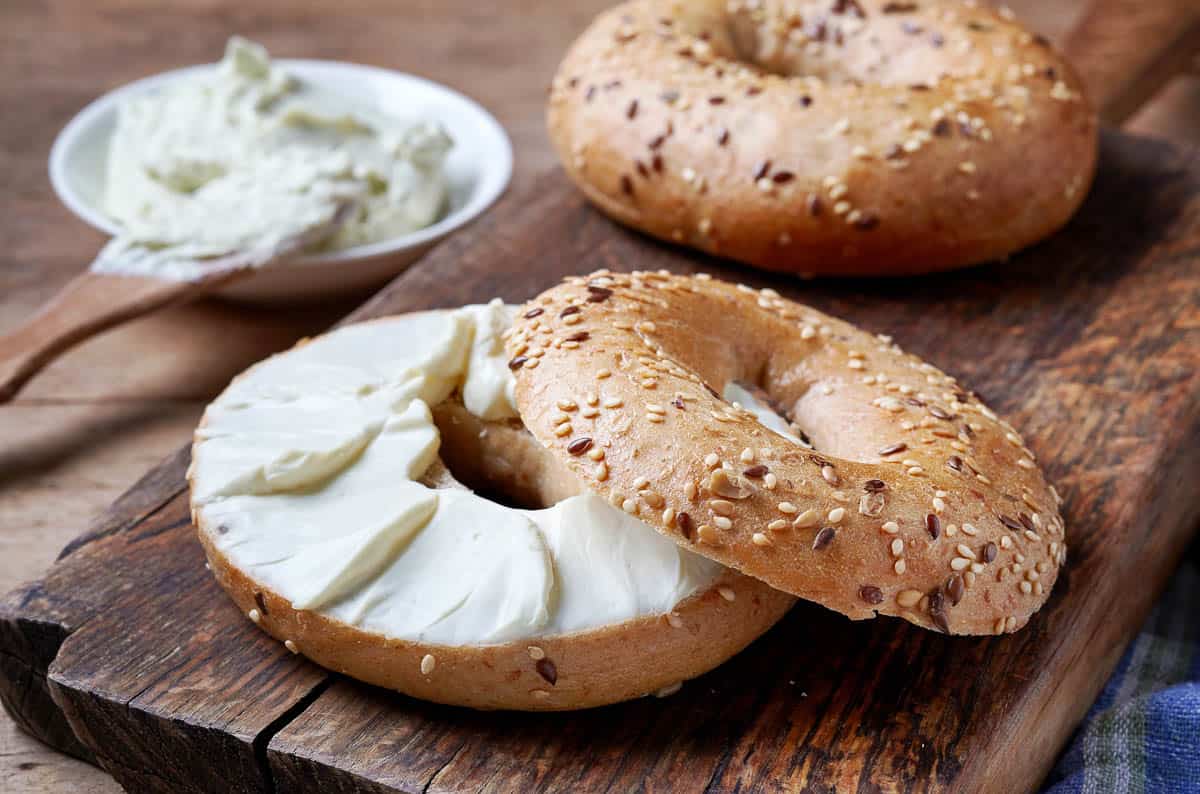 Bagel with cream cheese on wooden table.