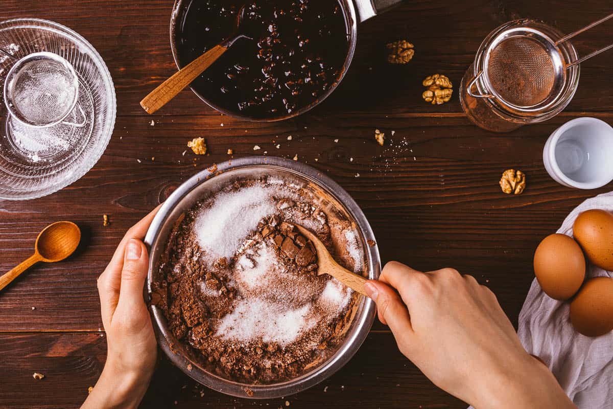 hands mix cocoa powder, sugar and flour for brownies