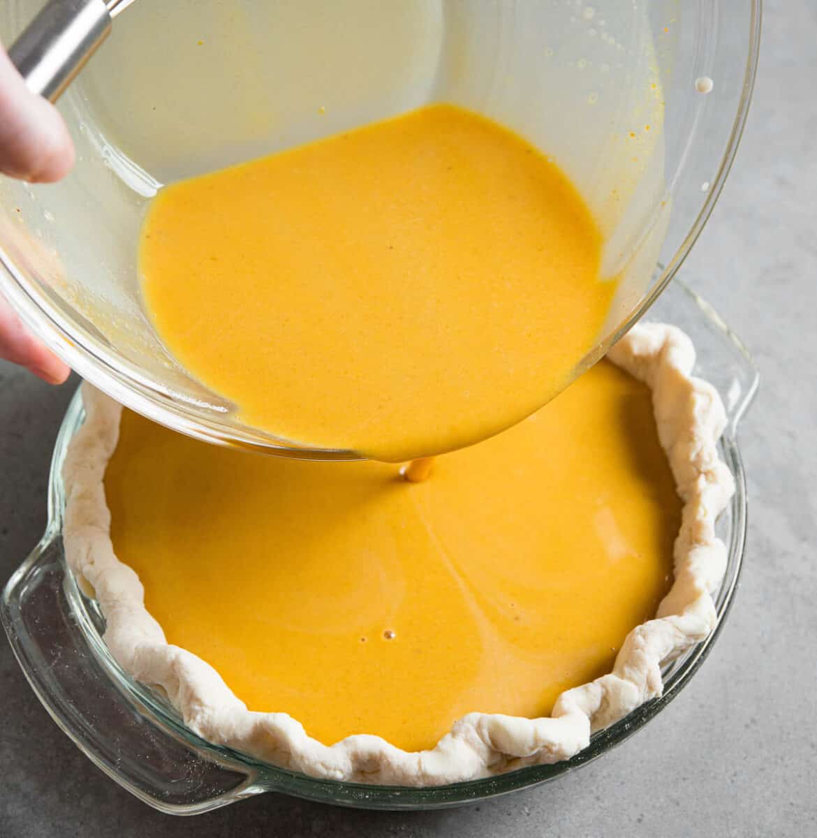 pouring pumpkin pie filling into shell