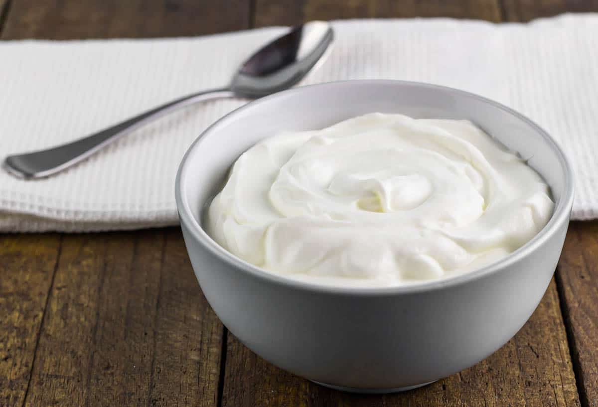 Natural creamy Greek yoghurt on wooden table background