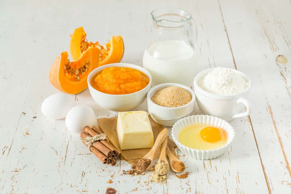 pumpkin pie ingredients in bowls on wood background.