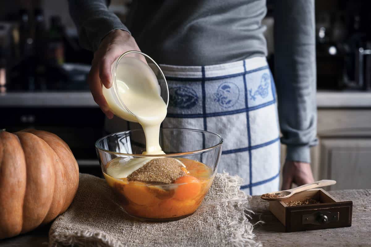 Adding condensed milk in the dough for pumpkin dump cake.