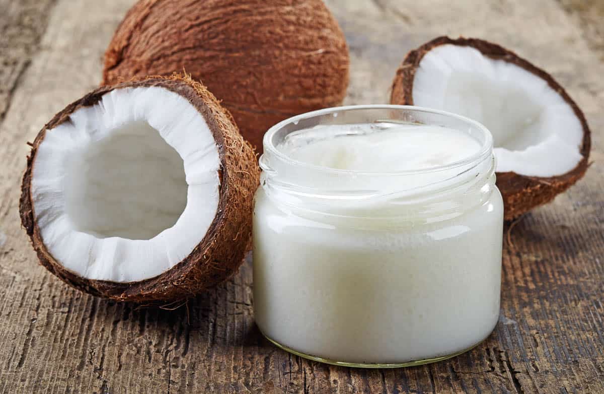 coconut oil and fresh coconuts on old wooden table.