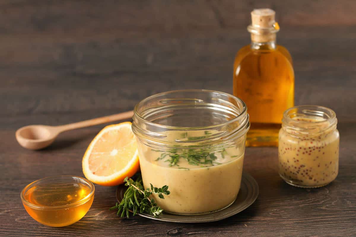 Homemade honey mustard dressing on wooden table.