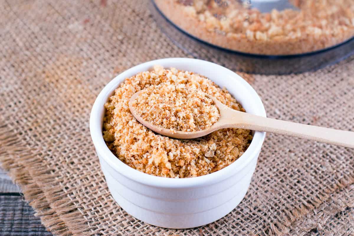 Bowl with bread crumbs on wooden table.