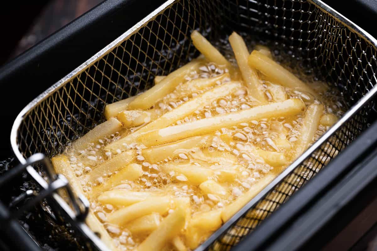 frying french fries in large fryer with oil.