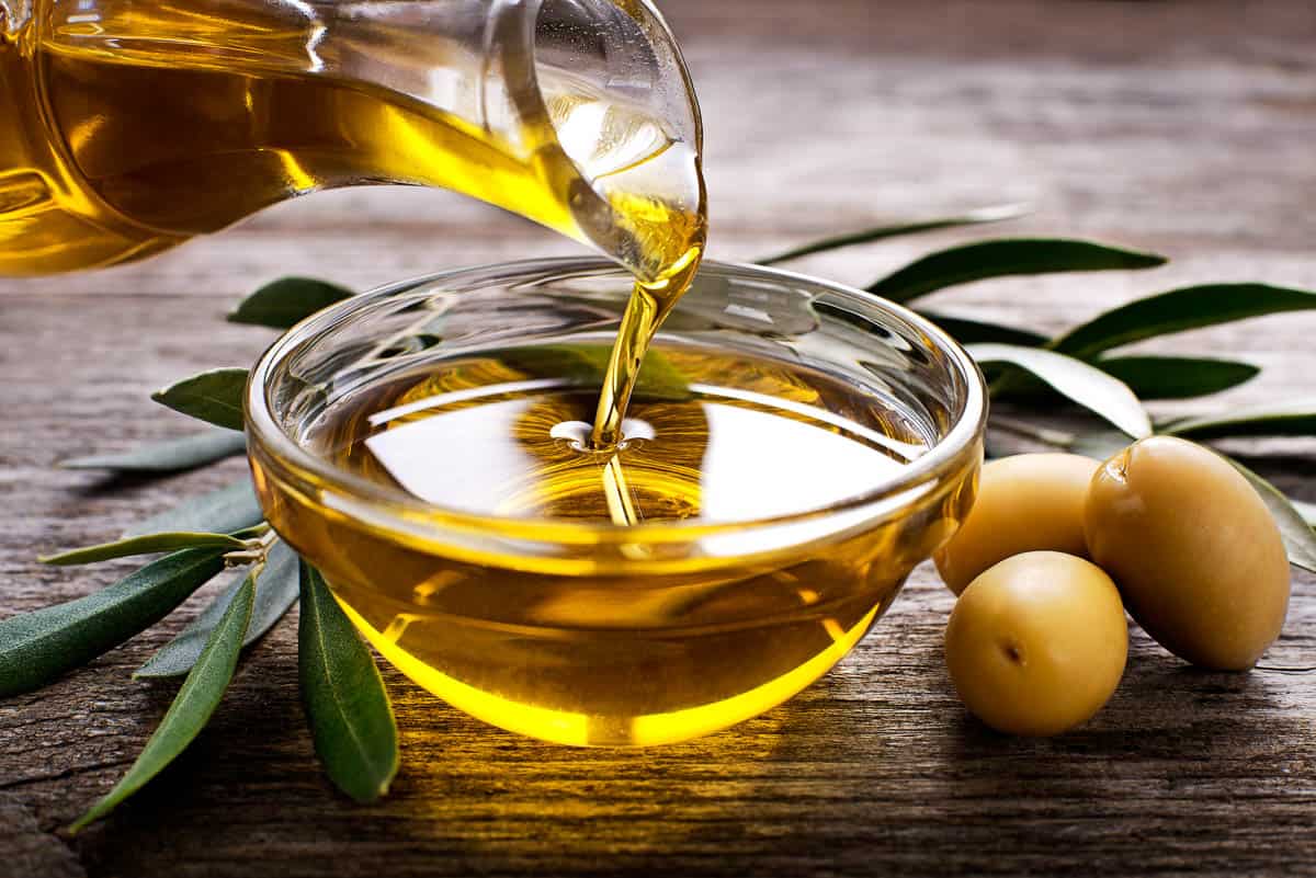 Bottle pouring virgin olive oil in a bowl close up.