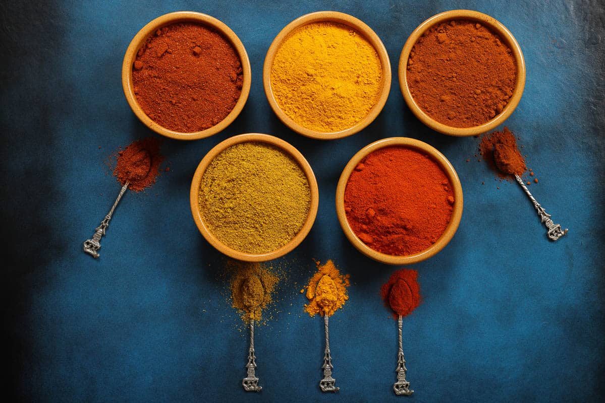 Curry Turmeric Paprika and Masala Powders on blue background, ingredients towards Indian Cuisine.