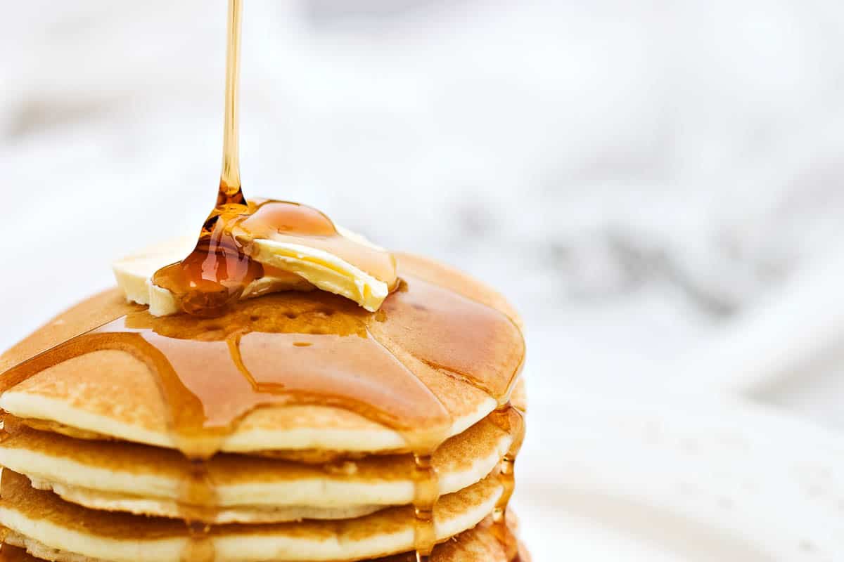 Maple syrup pouring onto pancakes.