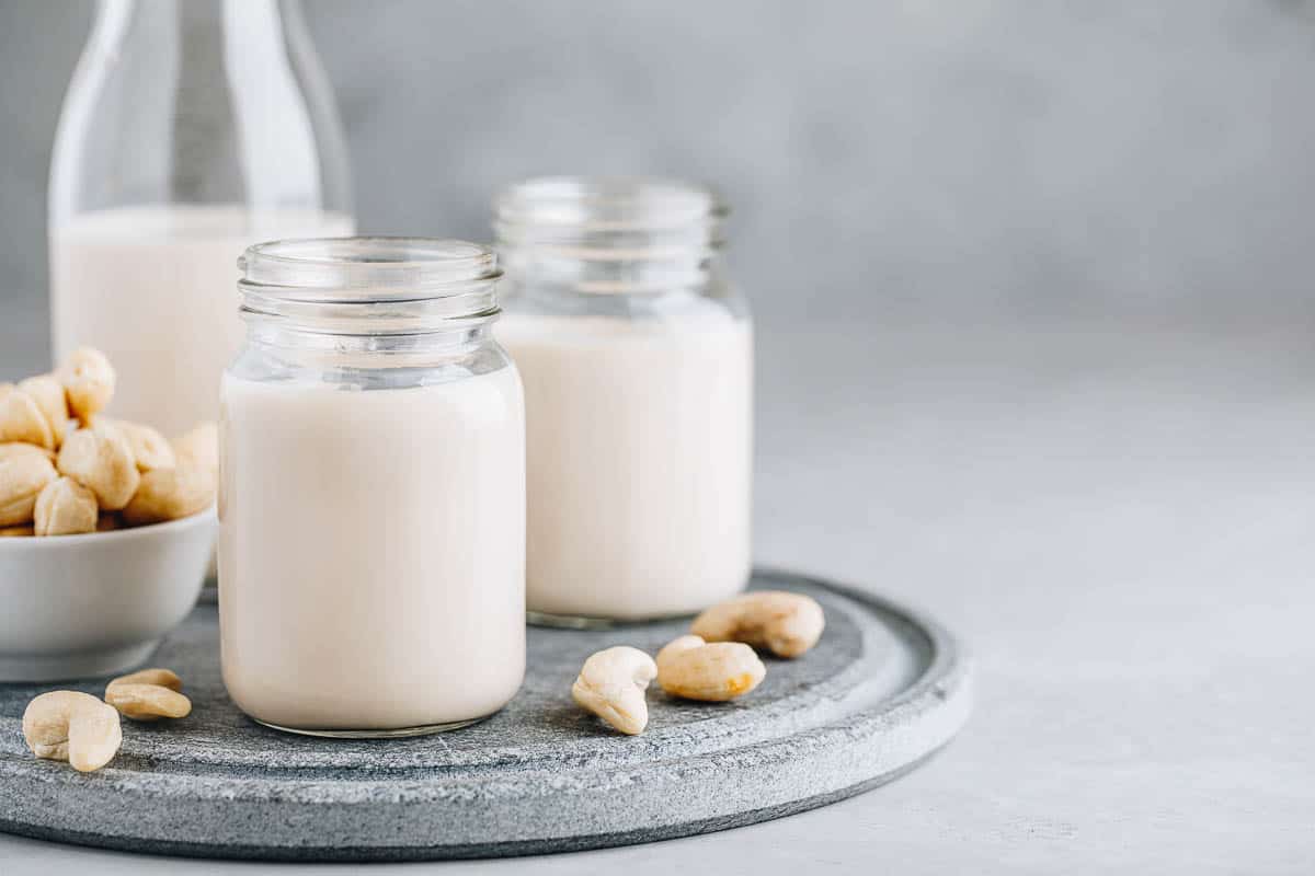 Cashew Nut Milk in glass on gray stone background.