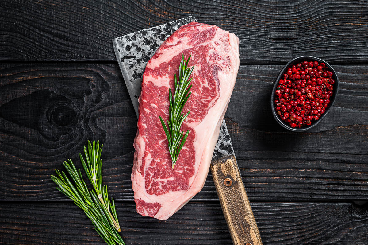 Fresh Raw new york strip beef steak on a butcher meat cleaver.