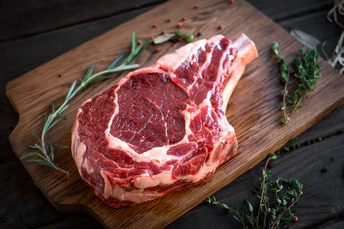 raw rib eye steak premium beef on bone on wooden chopping Board.