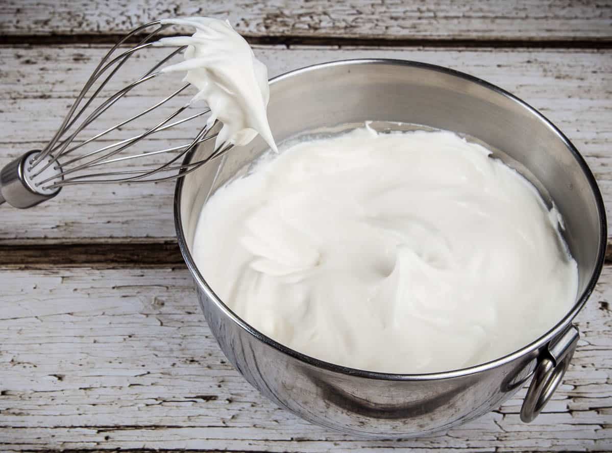 Bowl of whipped cream and whisk.