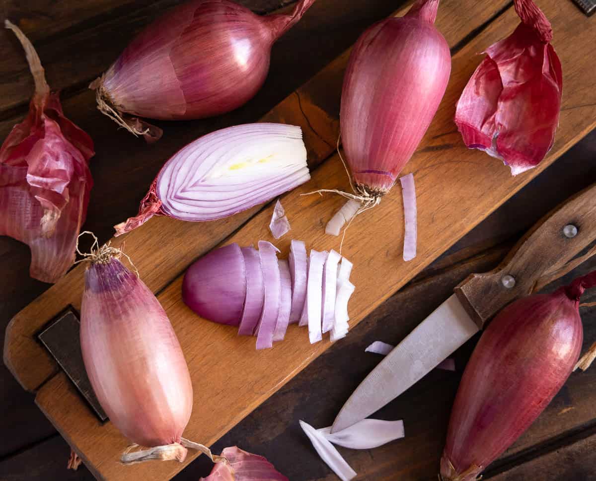 Sliced Red tropea onions with a knife on a wooden board.