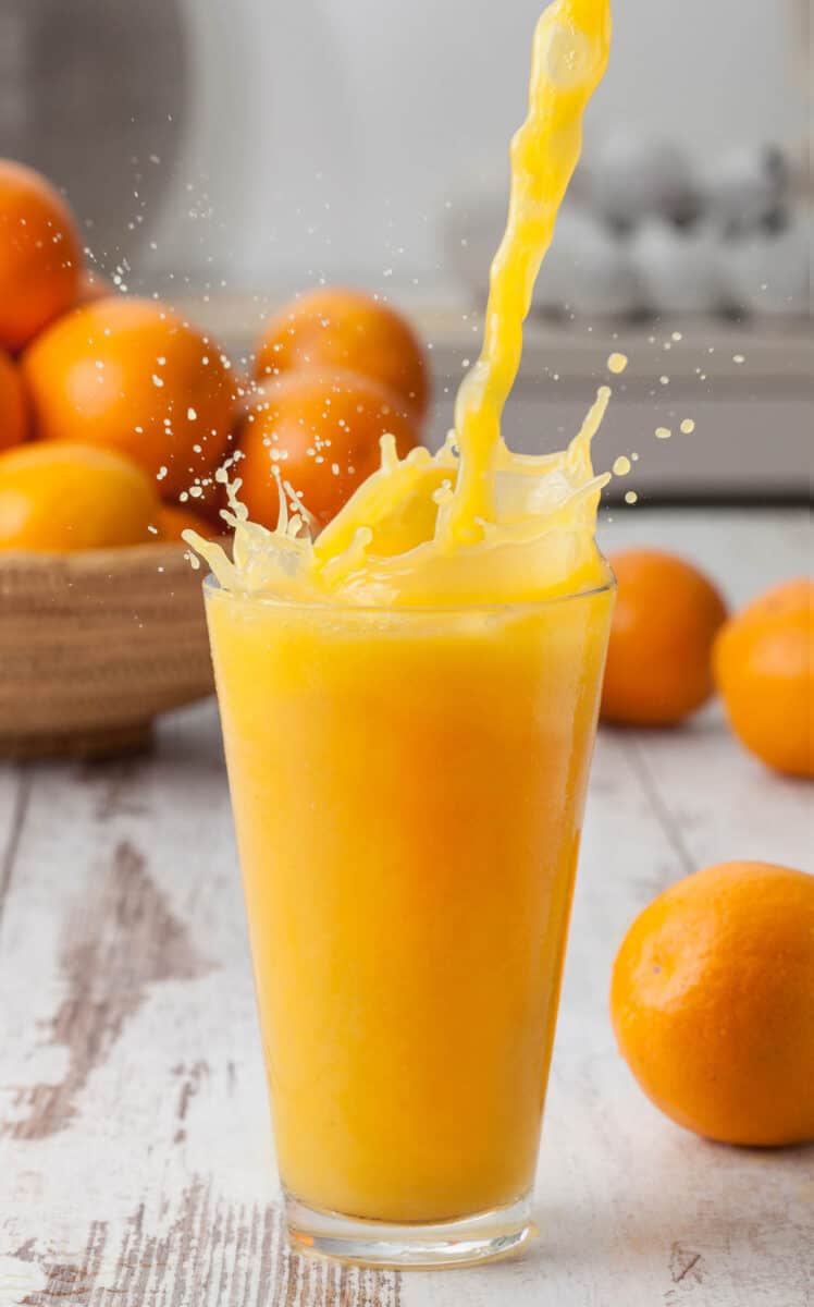 Pouring a glass of orange juice creating splash