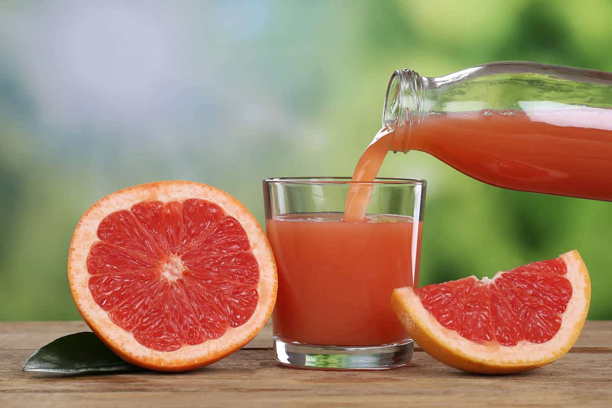 Grapefruit juice pouring into a glass.